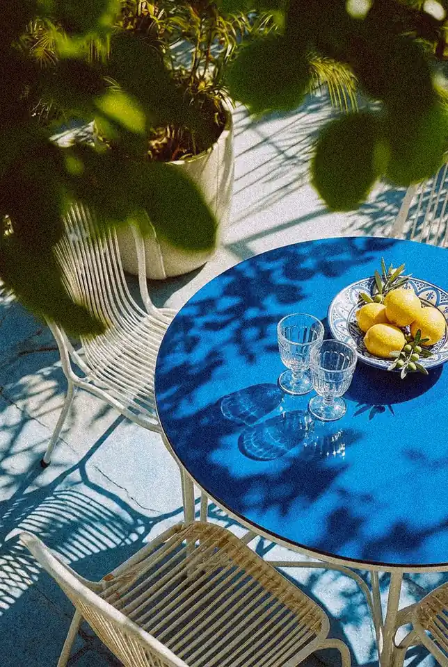 A sunlit terrace table for two with glasses and a bowl of lemons, chairs pulled up ready for a conversation