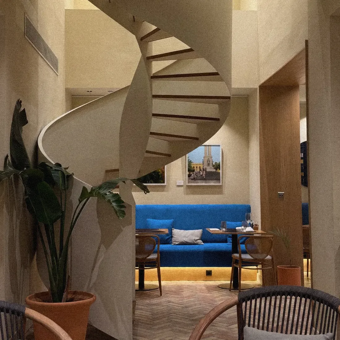 Hotel lounge with a sculptural spiral staircase and blue banquette