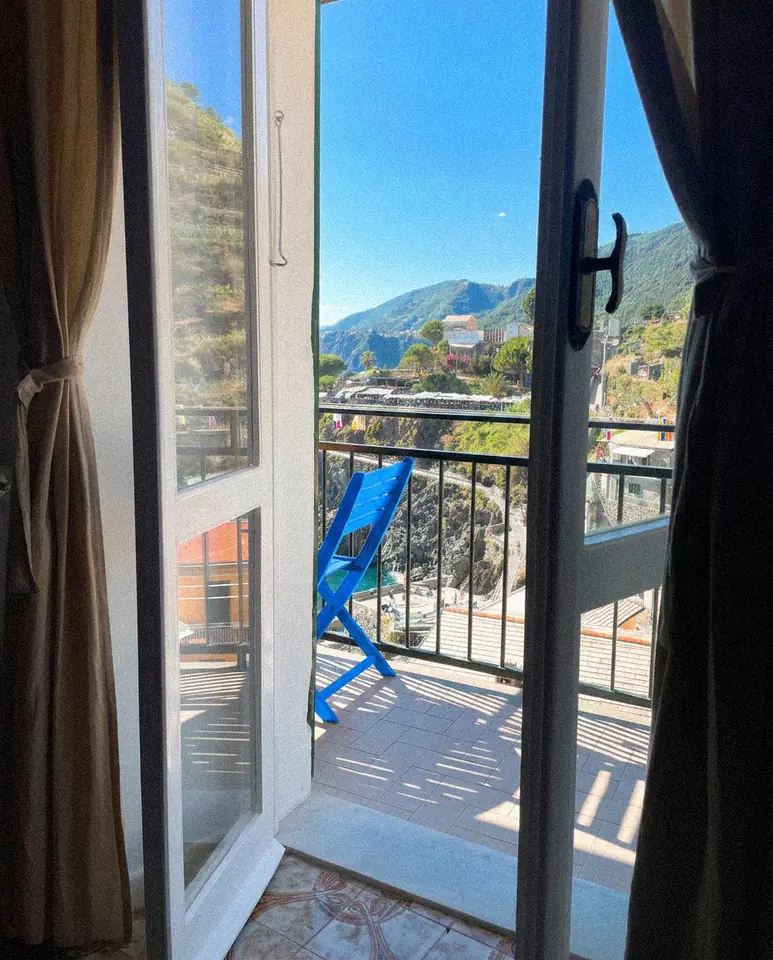 Balcony doors open to a blue chair and mountain view